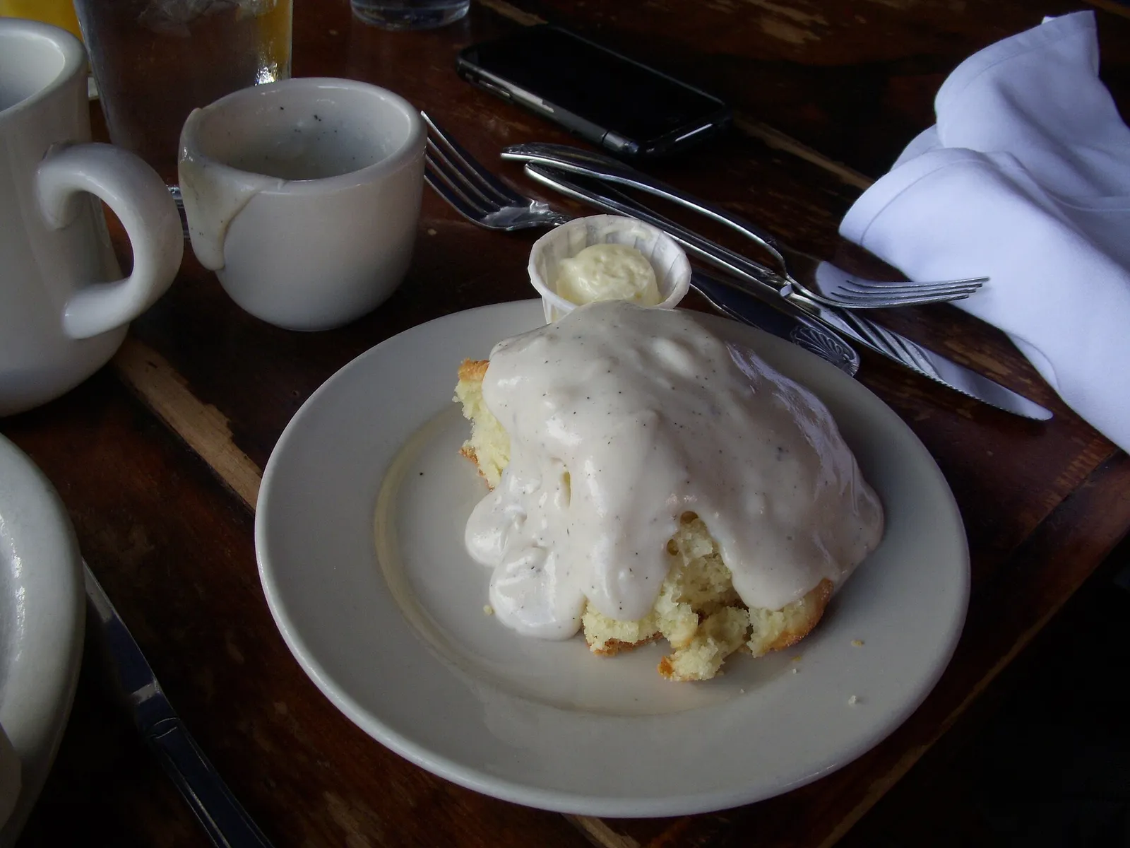A biscuit with gravy and a cup of coffee on a cafe table. The photo was not taken at a Columbus restaurant.