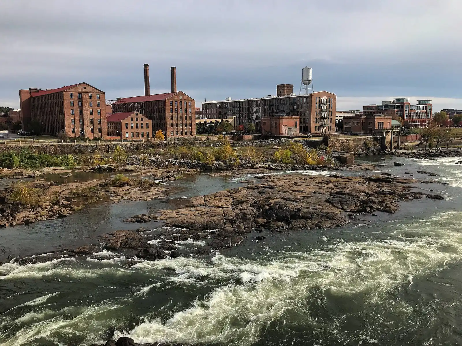 Uptown Columbus' riverfront mills and the Chattahoochee River rapids, seen from across the river.